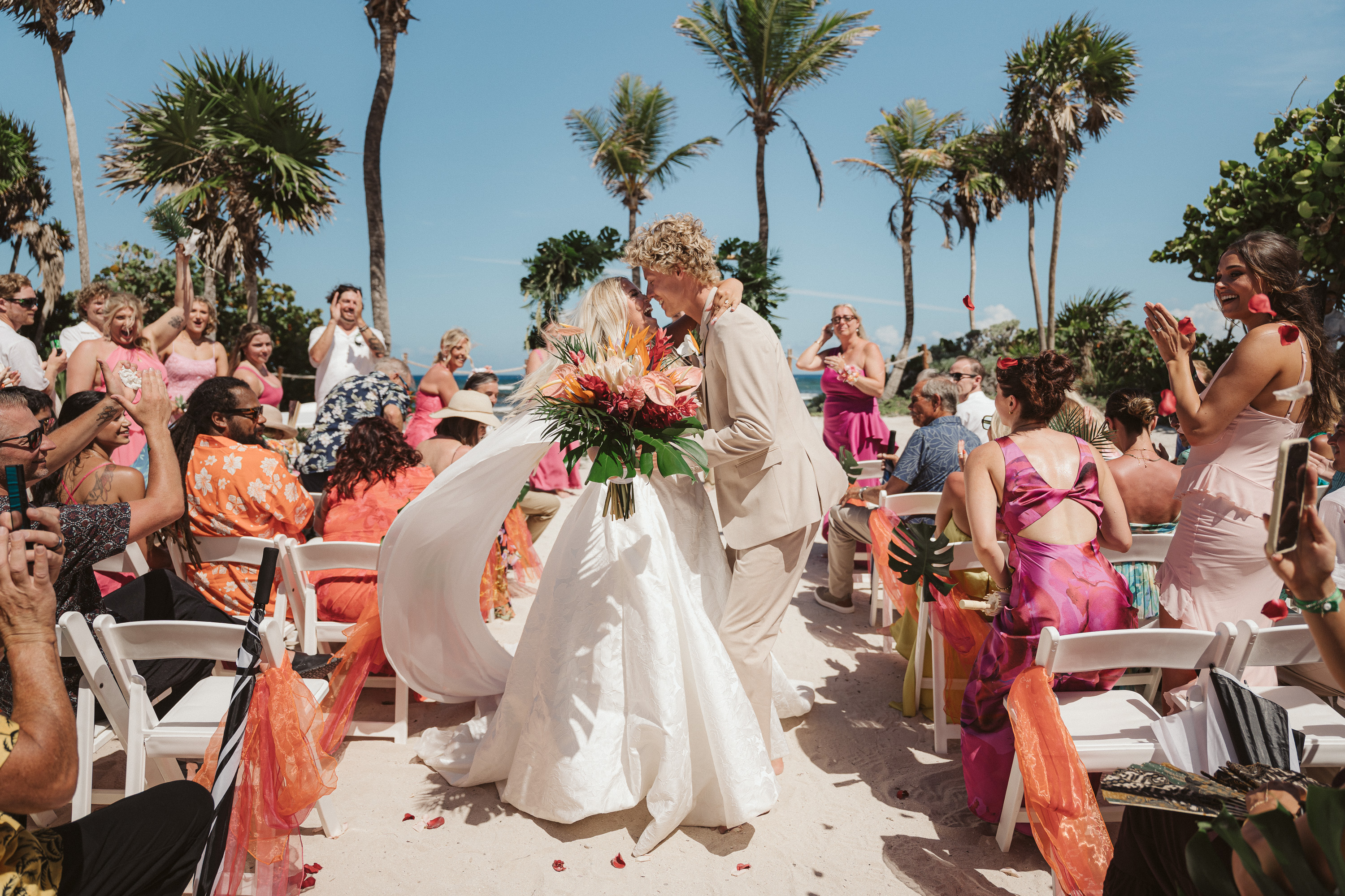 Guests cheering as newlyweds share their first kiss during a destination wedding ceremony in Riviera Maya, Mexico