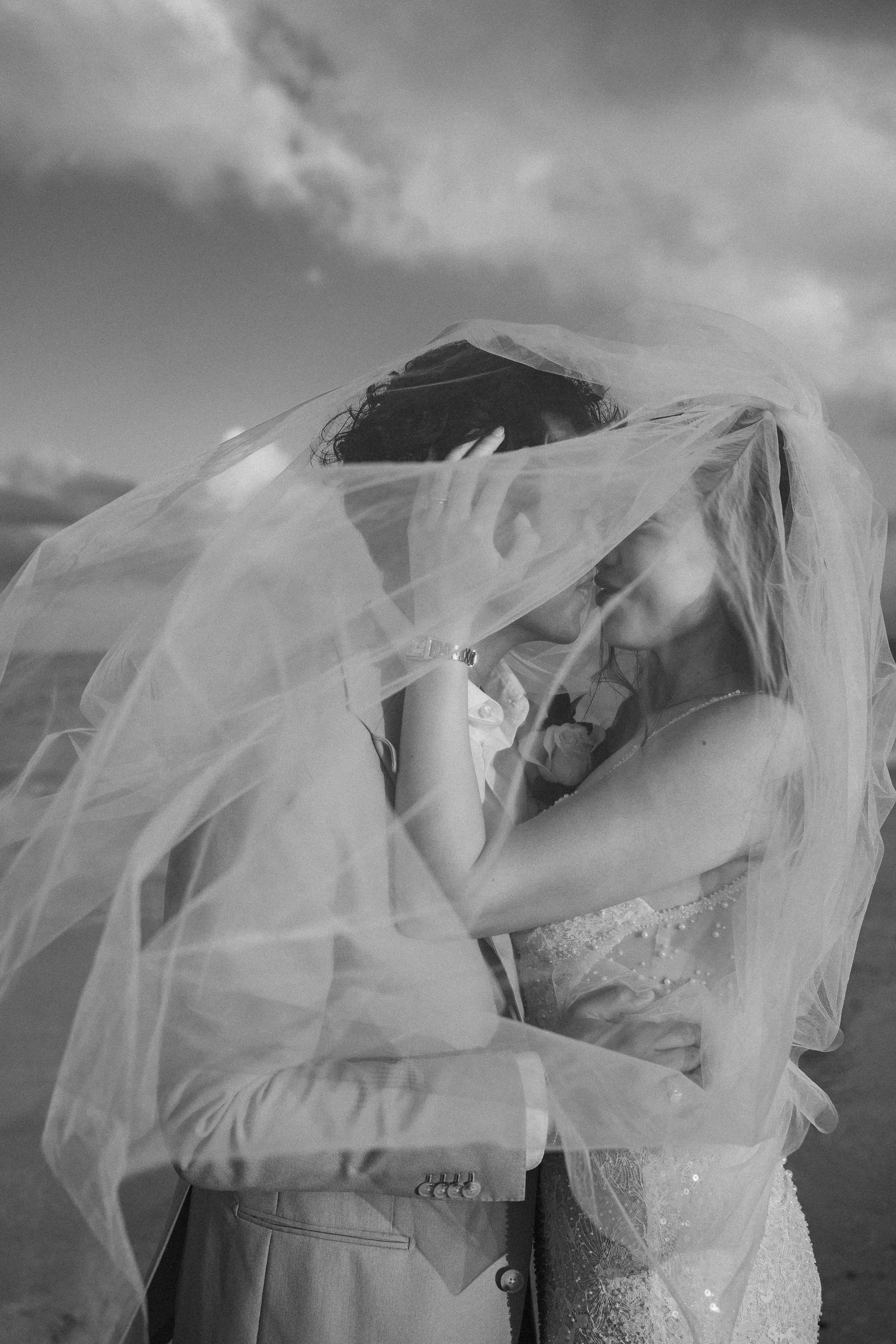 Bride and groom sharing a kiss beneath the wedding veil during their destination wedding in Cancun, Mexico.